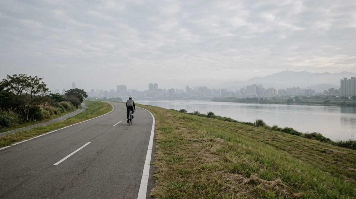 A wide riverside bike path along the Tamsui River in the morning with the city skyline behind on a Taipei bike tour, Taiwan